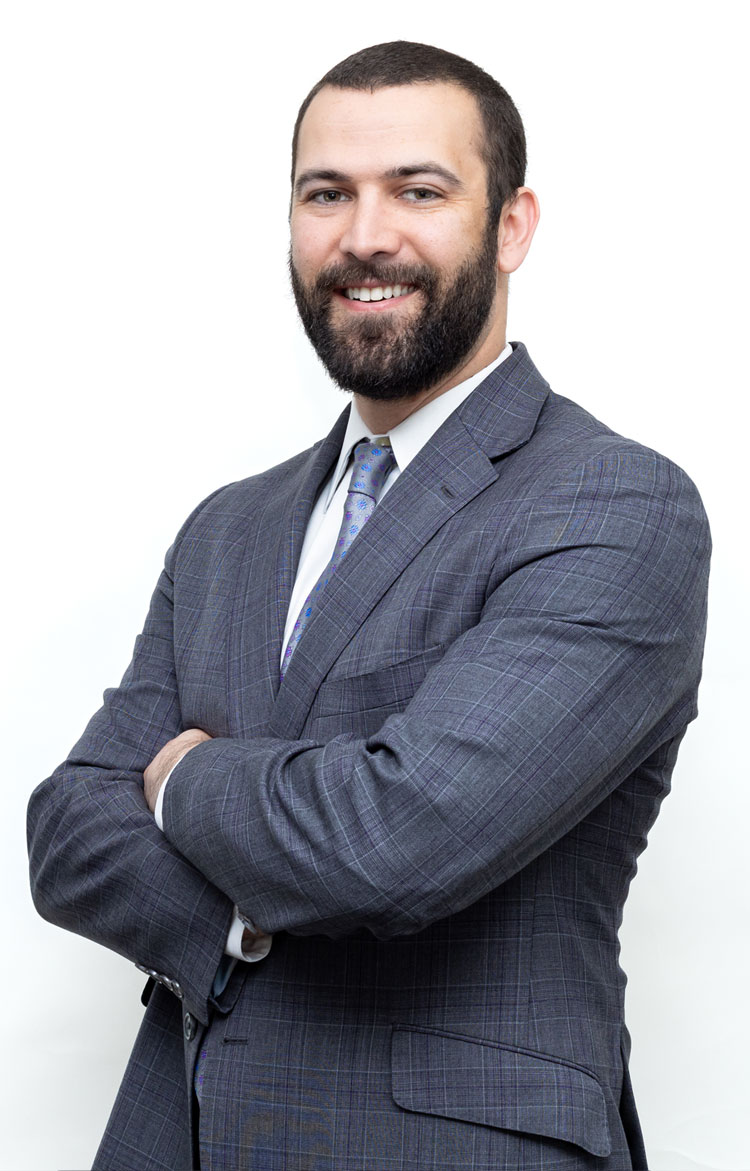 Andrew M. Klaas Andrew M. Klaas | Smiling man in a gray plaid suit with arms crossed, posing for a professional headshot.